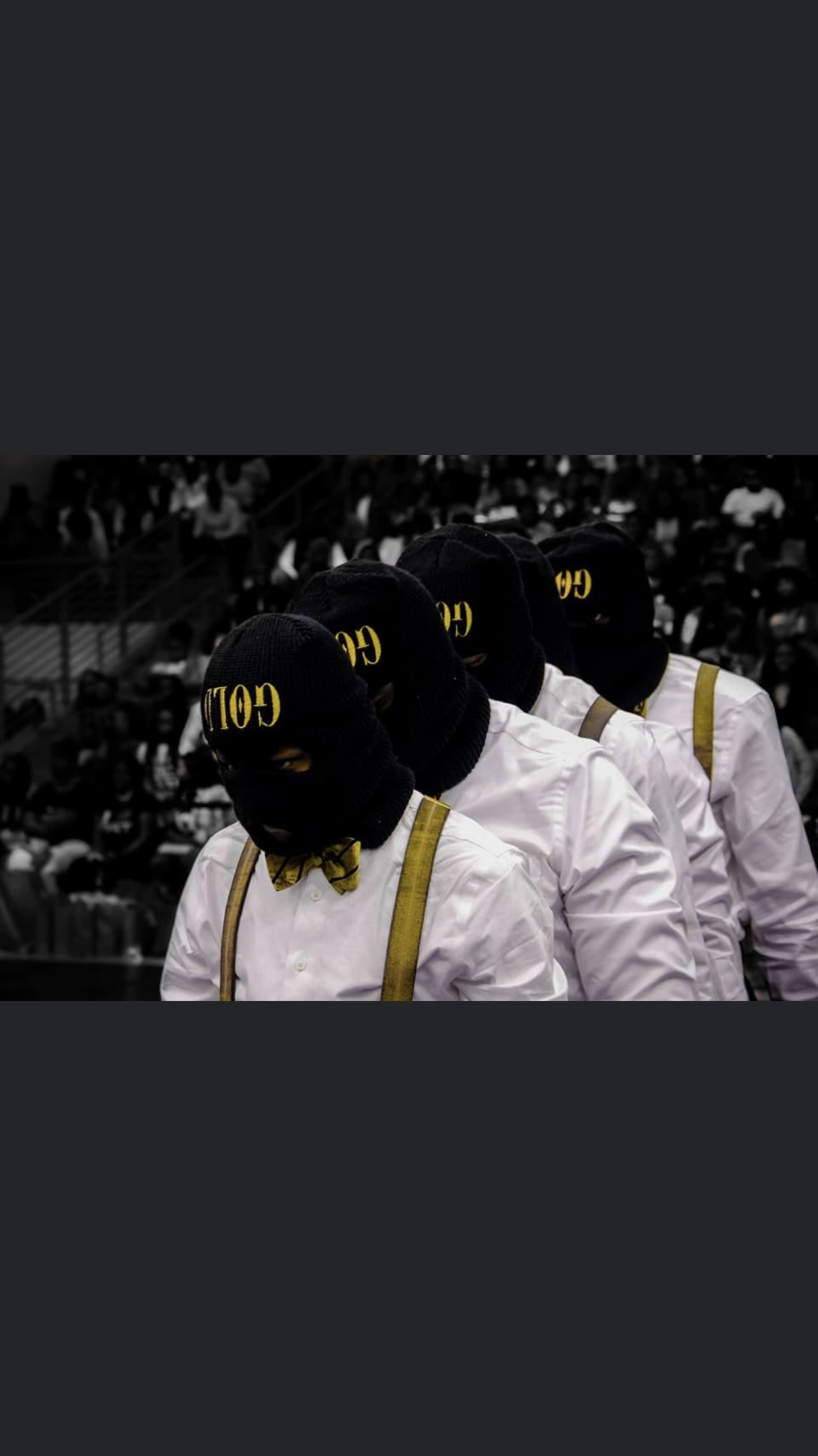 The Spring 2018 D.G.A.F line in an arena, standing in profile with heads bowed, wearing white dress shirts, gold bow ties and suspenders, and black ski masks reading GOLD.
