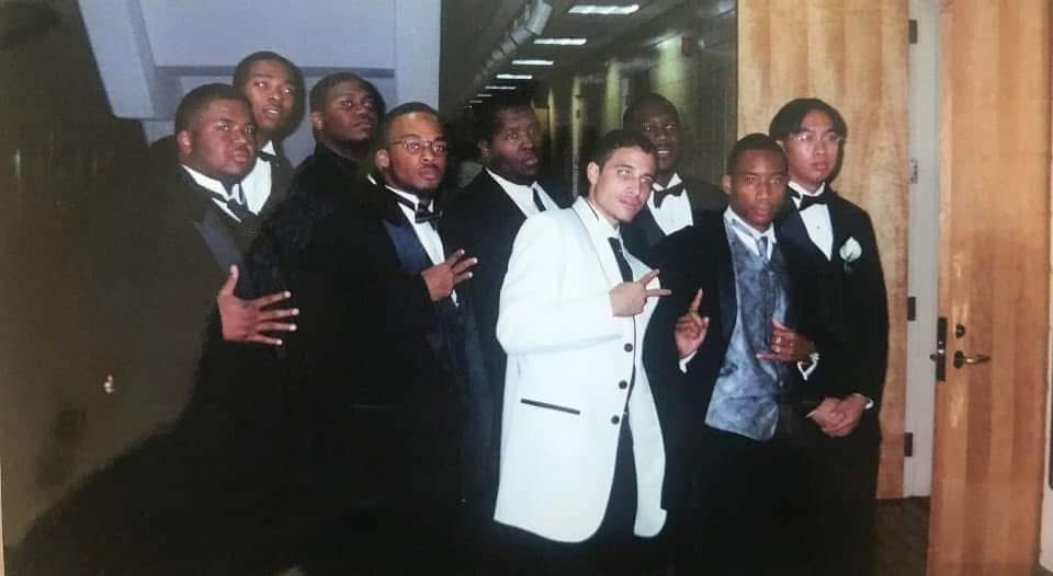 Legends of the Fall brothers in tuxedos posed in a hallway, throwing fraternity signs.